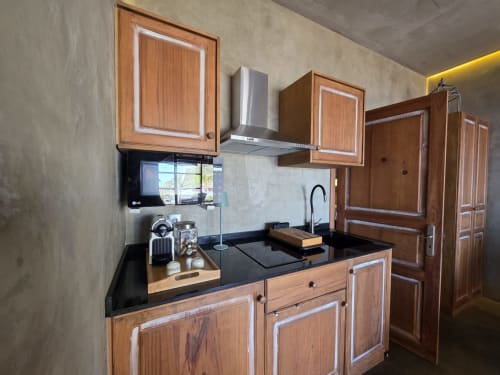 Cocina moderna con gabinetes de madera, encimera negra, campana de acero inoxidable y microondas LG en Les Terrasses Les