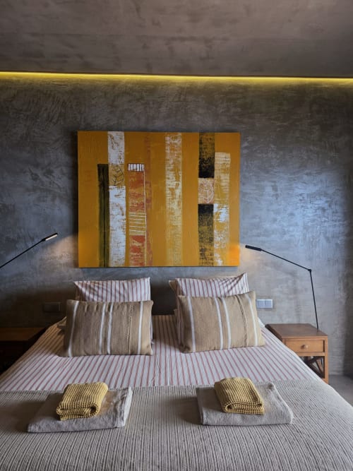 Suite de hotel moderno en Les Terrasses Les Suites con obra de arte abstracta dorada, ropa de cama a rayas y diseño contemporáneo