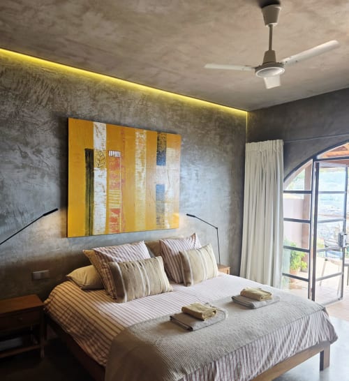 Habitación suite moderna en Les Terrasses Les Suites en Calheta con obras de arte amarillo, ropa de cama a rayas y terraza con vistas al