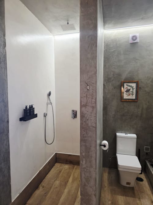 Baño moderno en suite Les Terrasses con ducha tipo walk-in, inodoro blanco, paredes texturizadas grises y acabados en madera
