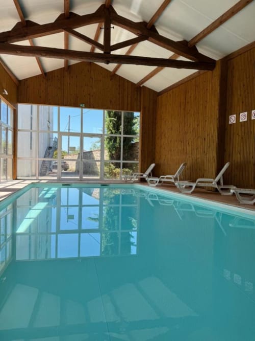Indoor swimming pool at Hôtel La Métairie in Cordes-sur-Ciel with lounge chairs and skylights