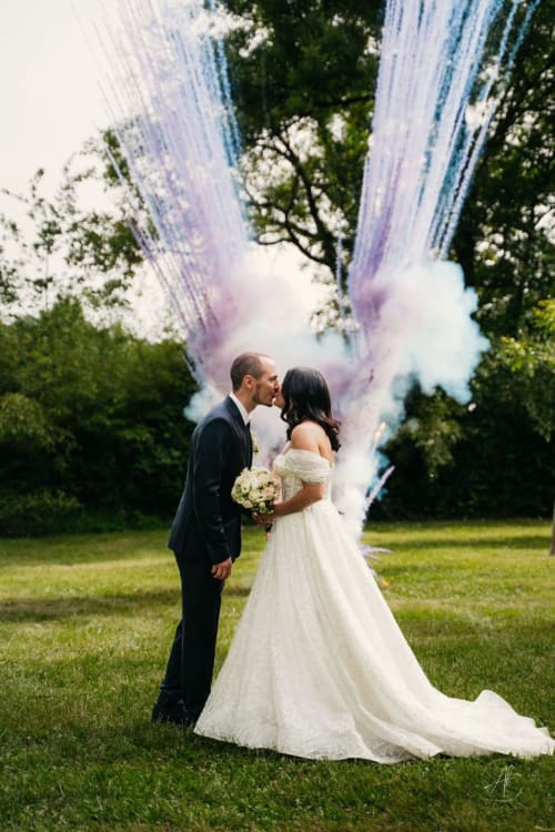Les mariés s'embrassent dans une explosion de poudre colorée au mariage de l'Hôtel La Métairie à Cordes-sur-ciel