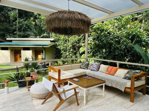 Terraza al aire libre de la Jaguar Room en Fauna Lodge con muebles de madera, lámpara colgante de paja y exuberantes vistas de la selva en Costa Rica