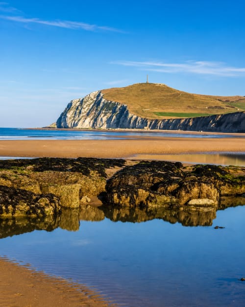 Dramatic white cliffs and sandy beach at Sangatte, near Ô de Mer hotel, with rocky pools and blue sky