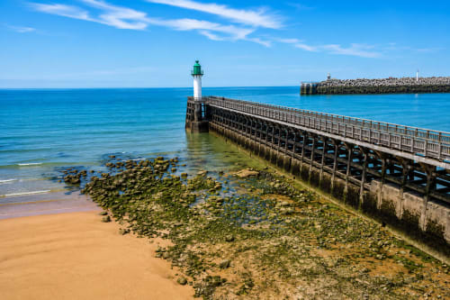Lighthouse and pier at Ô de Mer, Sangatte beach with turquoise waters and sandy shore
