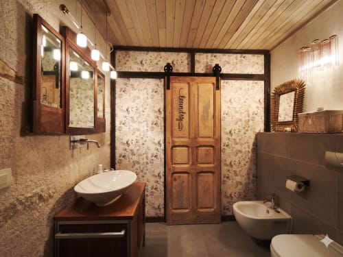 Salle de bains luxueuse de l'hôtel Viento de Ladera à Ségovie avec vasque en bois, lavabos sur plan, carreaux en terrazzo et porte en bois.