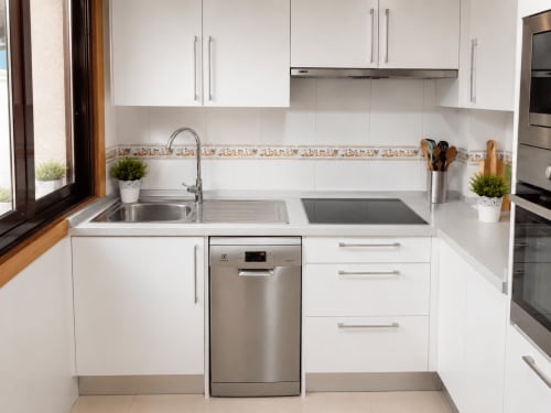 Cocina blanca y moderna del hotel Holibai en Baiona con electrodomésticos y fregadero de acero inoxidable