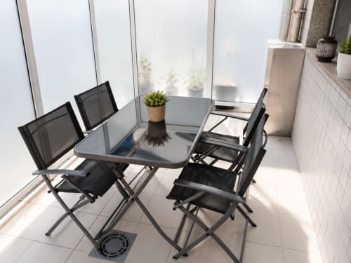 Moderna zona de comedor en la terraza con sillas negras y mesa de cristal con vistas a Baiona en el hotel Holibai