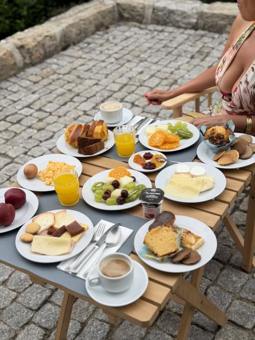 Mesa de café da manhã ao ar livre na Quinta das Susandas com pastéis, queijo, fruta e café em Tresouras, Portugal