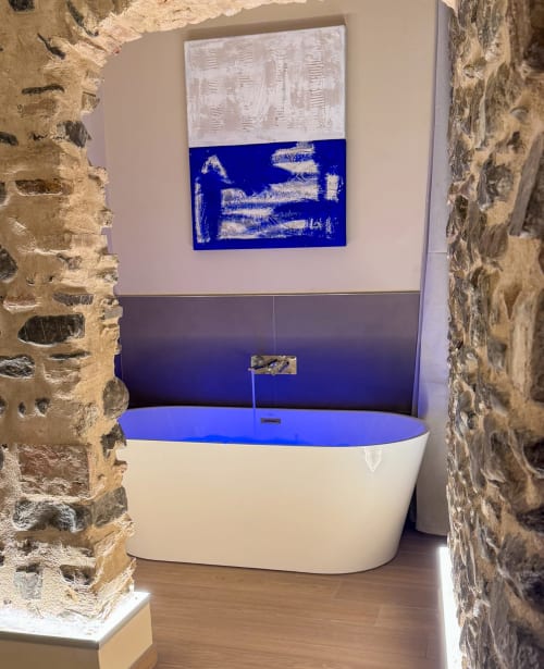 Modern bathtub with blue water feature at Talking Stones B&B, Dolceacqua, framed by rustic stone walls