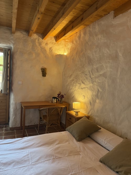 Dormitorio rústico en Casa Aldea L'Ayalga de Infiesto con vigas de madera vista, muros de piedra y vistas a las montañas