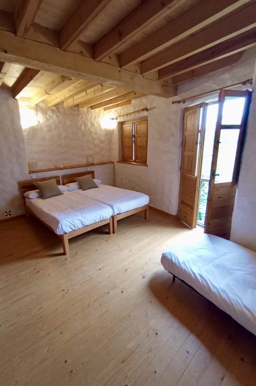 Amplio dormitorio familiar en Casa Aldea L'Ayalga con vigas de madera, dos camas y vistas al jardín en Infiesto