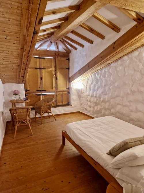 Dormitorio rústico con vigas de madera en Casa Aldea L'Ayalga en Infiesto, equipado con cama, escritorio y claraboya