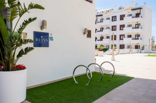 Entrada del spa Bliss en Haus Holiday Homes San Pedro del Pinatar con edificio de apartamentos blanco y aparcabicicletas