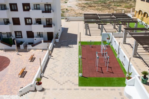 Vista aérea del complejo Haus Holiday Homes con cancha de tenis, tumbonas, pérgolas y edificio blanco en San Pedro