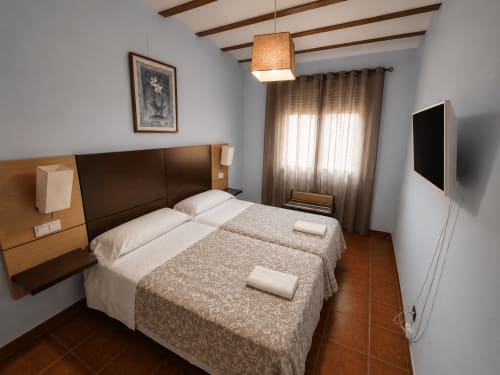 Dormitorio moderno en villa de dos habitaciones de Finca El Arroyo, Alcaraz, con dos camas, televisor de pantalla plana y vigas vistas