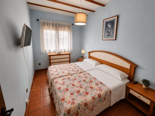 Dormitorio luminoso en villa Finca El Arroyo de Alcaraz con camas gemelas, muebles de madera y televisor
