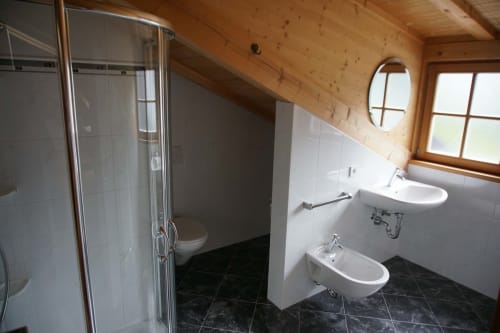 Bagno moderno negli appartamenti loft Rusctlea con doccia, doppio lavabo, bidet e soffitto in legno a Selva di Val Gardena