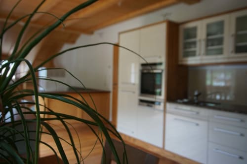 Cucina moderna nell'appartamento The Loft di Rusctlea Apartments a Selva di Valgardena, con mobili bianchi e travi in legno