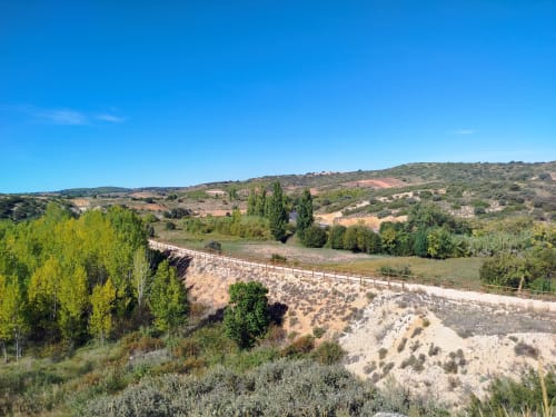 Paisaje rural pintoresco en Finca El Arroyo de Alcaraz, España, con colinas ondulantes, vegetación exuberante y arquitectura rústica