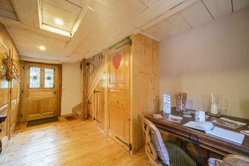 Wooden cottage entryway with rustic pine furniture, desk, and stairs at Les Ambrades in Eguisheim