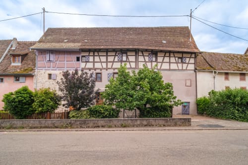 Half-timbered cottage exterior in Eguisheim, France with pink stucco walls and traditional architecture