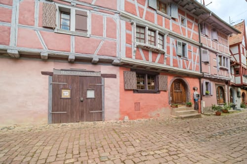 Half-timbered medieval buildings in Eguisheim village square, Chez Ambre cottage exterior with wooden doors