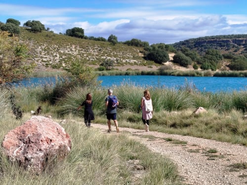 Huéspedes caminando junto a un lago turqueso en Finca El Arroyo en Alcaraz, rodeado de colinas ondulantes y vegetación autóctona