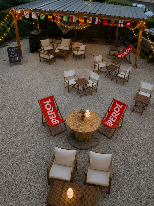 Espace de détente en plein air de l'Hôtel de Champagne avec sièges Perrol, guirlandes lumineuses et drapeaux internationaux à Saint-Dizier