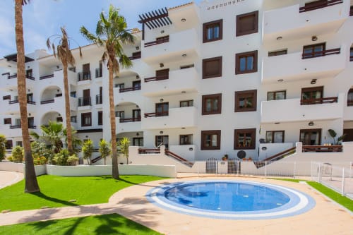 Moderno edificio blanco con piscina y palmeras en San Pedro del Pinatar, España