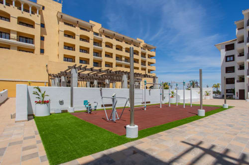 Área de fitness al aire libre en Haus Holiday Homes de San Pedro del Pinatar con equipos de ejercicio, césped verde y apartamento amarillo