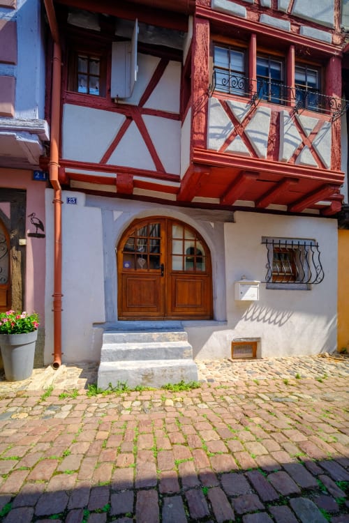 Les Ambrades villa entrance in Eguisheim with red half-timbered facade and wooden door