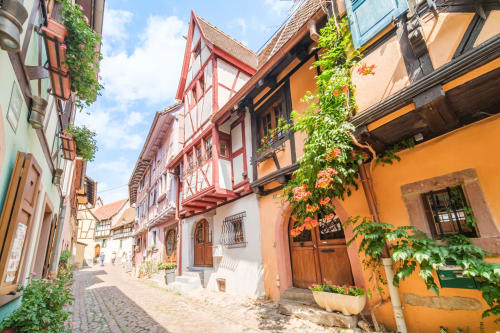Charming cobblestone street in Eguisheim with half-timbered buildings and ivy-covered walls at Les Ambrades hotel
