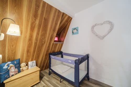 Cozy baby room at Les Ambrades villa in Eguisheim with wooden accent wall, portable crib, and nursery décor