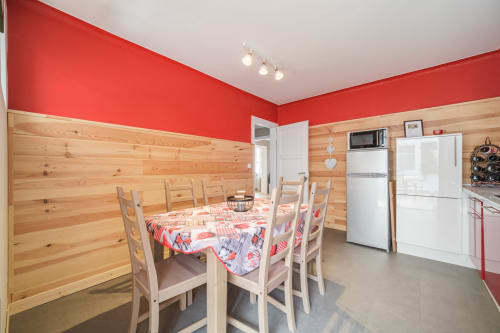 Modern kitchen and dining area at Le Cépage de Sigo apartment in Kaysersberg Vignoble with red walls, wooden paneling, and