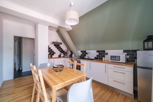 Modern kitchen-dining area in Le Coteau de Sigo apartment, Kaysersberg Vignoble, with wooden table and white cabinetry