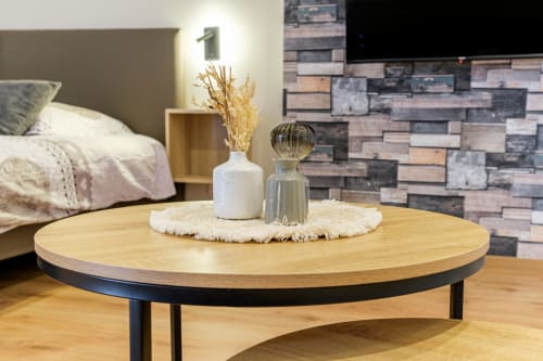 Modernes Schlafzimmer mit rundem Holzcouchtisch, weißer Keramik-Vase und Glasdeko auf rundem Teppich im Ferienhaus Les Ambrades