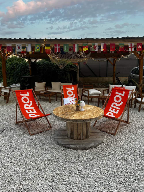 Chaises longues Aperol et table en bois dans le patio de la cour de l'Hôtel de Champagne à Saint-Dizier avec drapeaux festifs