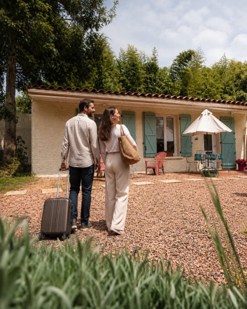 Couple arriving at Le Clos Bussy cottage in Bellerive-sur-Allier with luggage and garden view