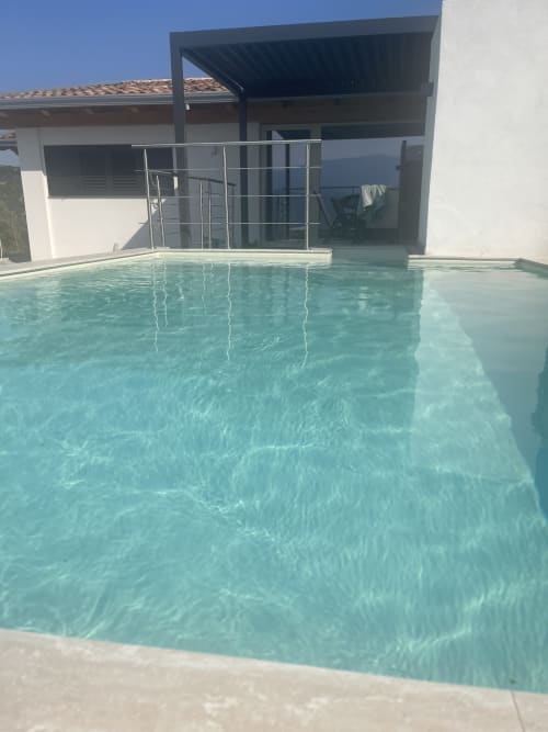 Piscina color turchese cristallino della Villa Maria con villa bianca moderna e ringhiere metalliche nella campagna di Cosenza