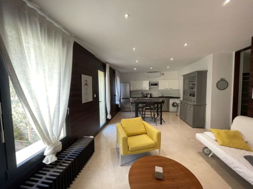 Appartement moderne à la Maison Dormoy Marseille avec fauteuil jaune, kitchenette et grandes fenêtres vue sur la ville