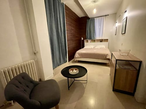 Studio moderne à la Maison Dormoy Marseille avec lit, fauteuil gris anthracite, table ronde et décoration épurée