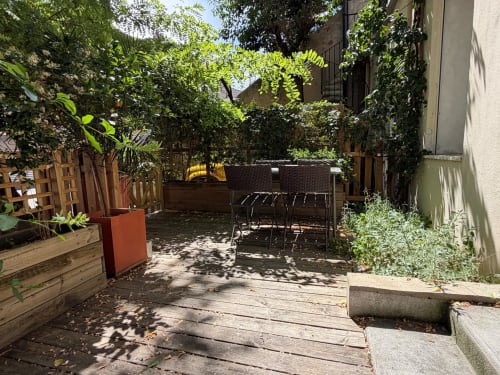 Terrasse privée de l'appartement Maison Dormoy à Marseille avec végétation luxuriante, terrasse en bois et coin salon ombragé