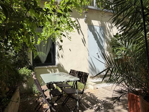 Cour ombragée avec coin salon à la Maison Dormoy, appartement marseillais avec table, chaises et verdure luxuriante