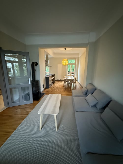 Salon moderne de la Villa58 chez Mattbnb Metz avec canapé gris, salle à manger, parquets et grandes fenêtres