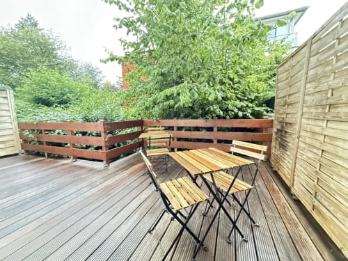 Terrasse extérieure de la Villa58 Mattbnb à Metz avec mobilier en bois, jardinières surélevées et clôture d'intimité
