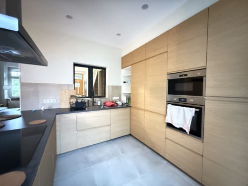 Cuisine moderne à la Villa58 Mattbnb à Metz avec armoires en bois clair, plan de travail noir et électroménagers intégrés