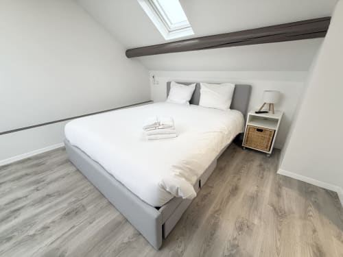 Chambre lumineuse à la Villa58 Mattbnb à Metz avec lit queen-size, puits de lumière, poutre apparente et table de nuit avec lampe