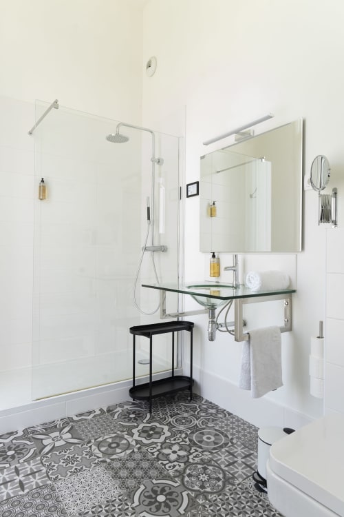Salle de bains moderne à la Maison Dormoy Marseille avec douche vitrée, vasque en verre vert, carrelage à motifs et miroir