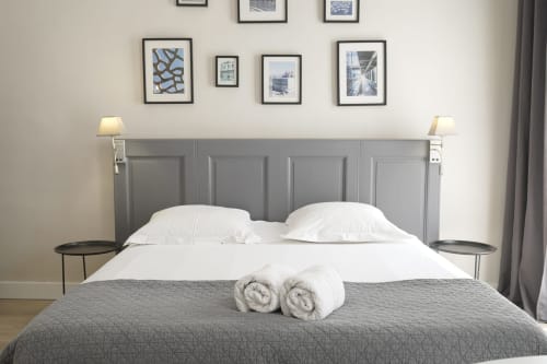 Chambre élégante à la Maison Dormoy à Marseille avec tête de lit grise, literie blanche, serviettes roulées et art urbain encadré